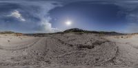 the view of a sand dune and the ocean from a fisheye lens, on a sandy beach