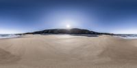 the beach is lined with sand and there are water coming up from the ocean and a small island in the distance