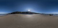 a large rock on top of a sandy beach on a clear day - shot using fisheye lens