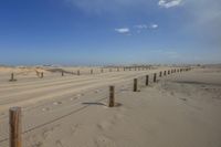 two beach fences are attached to poles in the sand dunes at the beach near some small rocks