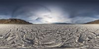 a panoramic view of a huge sandy area under cloudy skies and sunbeams