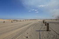 there is a large sandy field with tracks in it and clouds above the land behind it