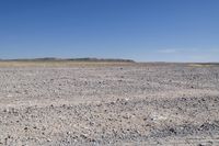 an orange fire hydrant sitting in the middle of a sandy field next to a desert area