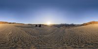 three people are walking through the sand in the desert at sunset in this view from a fish eye lens