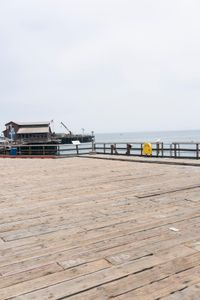 the wooden floor of a pier with a yellow surf board in the water behind it