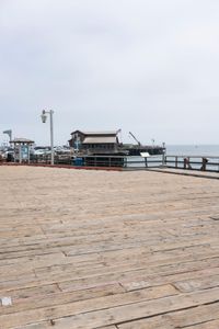 the wooden floor of a pier with a yellow surf board in the water behind it