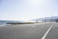 a bike rides down the highway next to the ocean and shore line at the end of a sunny day