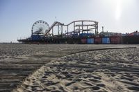 an empty beach area with sand and a ferris wheel in the background of the photo