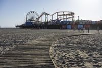 an empty beach area with sand and a ferris wheel in the background of the photo