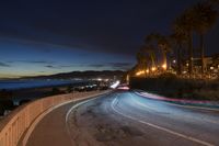 the coast with waves is at the right of this photo, a person riding his motorcycle on the street