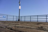 an empty pier fence sitting next to the ocean and a street light on it's post