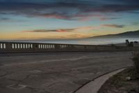 the coast with waves is at the right of this photo, a person riding his motorcycle on the street