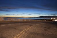 the coast with waves is at the right of this photo, a person riding his motorcycle on the street