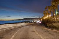 the coast with waves is at the right of this photo, a person riding his motorcycle on the street