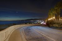 the coast with waves is at the right of this photo, a person riding his motorcycle on the street