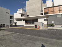 a parking lot with a cement building and an asphalt parking area beside it has many windows