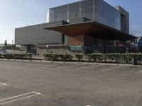 large parking lot with multiple cars parked in front of it with glass walls and windows