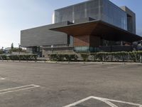 large parking lot with multiple cars parked in front of it with glass walls and windows