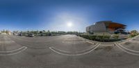 a parking lot and large white building are seen through the fish eye lens lens of this image