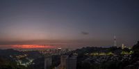 buildings, a clock tower, and lights are lit at dusk over the city of sao do sul