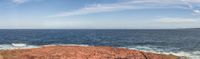 an orange rock on top of a body of water next to waterline with clouds