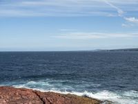 an ocean view from a high point near the shore with two waves crashing against rocks