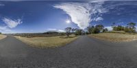 two large panoramic screens have different skies and clouds in them and a wide, straight road leads out to the distance