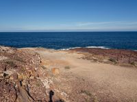 the person stands on top of a rocky cliff next to the ocean in the distance