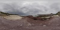 a distorted lens image with multiple rocks on the beach in the background and a person looking down