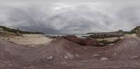 a distorted lens image with multiple rocks on the beach in the background and a person looking down