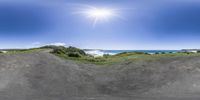 the view from inside a skateboard ramp looking down at the water and a bright sun on a blue sky above