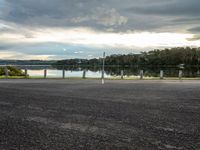 the road looks straight ahead, along with some trees by the water and the grass is on the side