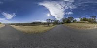 two large panoramic screens have different skies and clouds in them and a wide, straight road leads out to the distance