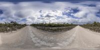 a wide angle view of a dirt track with a cloudy sky background and the camera on the left side of it