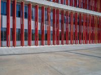 a concrete structure made into rows of orange and yellow poles are on a cement sidewalk