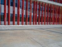 a concrete structure made into rows of orange and yellow poles are on a cement sidewalk