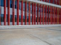 a concrete structure made into rows of orange and yellow poles are on a cement sidewalk