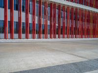 a concrete structure made into rows of orange and yellow poles are on a cement sidewalk