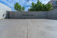 the empty parking lot in front of a wall with apartment buildings on it and a skateboarder on a ramp