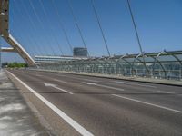 a truck driving across a bridge near a street corner near buildings and a bridge with many cables