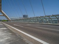 a truck driving across a bridge near a street corner near buildings and a bridge with many cables