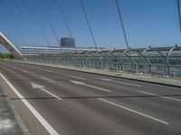 a truck driving across a bridge near a street corner near buildings and a bridge with many cables