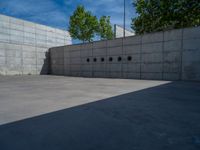 the empty parking lot in front of a wall with apartment buildings on it and a skateboarder on a ramp