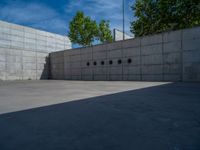 the empty parking lot in front of a wall with apartment buildings on it and a skateboarder on a ramp