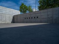 the empty parking lot in front of a wall with apartment buildings on it and a skateboarder on a ramp