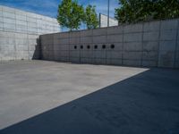 the empty parking lot in front of a wall with apartment buildings on it and a skateboarder on a ramp