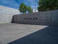 the empty parking lot in front of a wall with apartment buildings on it and a skateboarder on a ramp