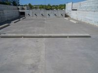 the empty parking lot in front of a wall with apartment buildings on it and a skateboarder on a ramp