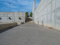 the empty parking lot in front of a wall with apartment buildings on it and a skateboarder on a ramp