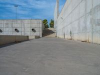 the empty parking lot in front of a wall with apartment buildings on it and a skateboarder on a ramp